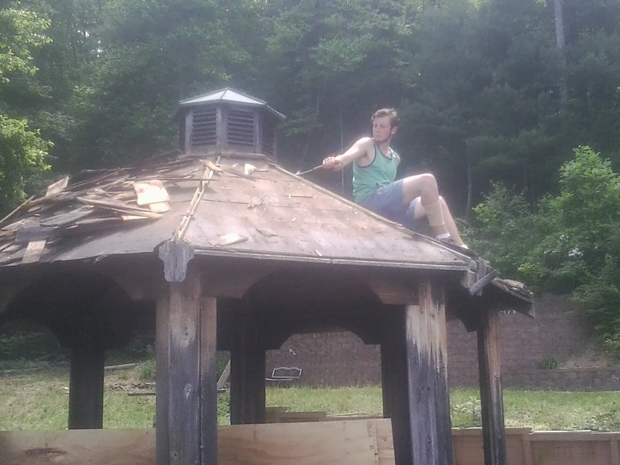 Tearing the old roof off a wooden gazebo before new shakes in Lignum