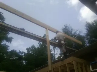 Carpenter setting a ridge beam over a new addition frame — Ice Dam Removal by Roofing Brothers in Lignum