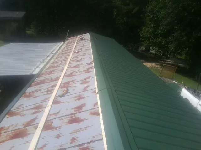Old rusted panels beside newly installed green metal roofing — Wind Damage Roof Repair by Roofing Brothers in Lignum