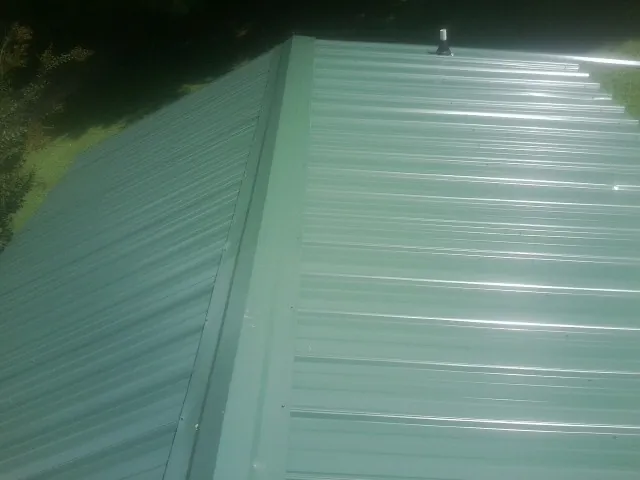New green metal panels meeting at the ridge of a roof — Flat Roof Repair work by our crew in Lignum