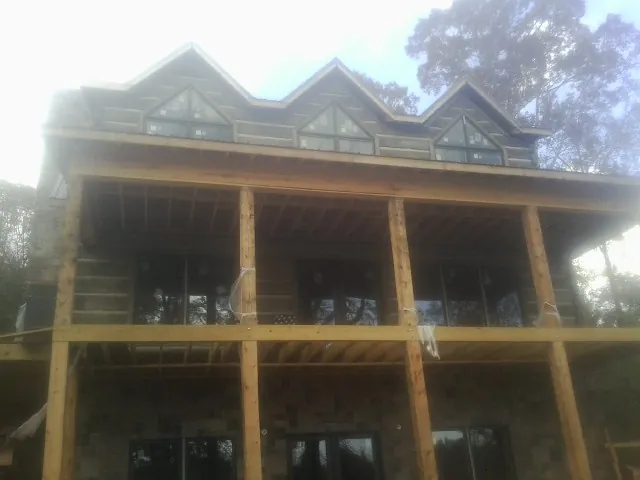 Dormers and porch framing on a large log home under construction — Roof Coating work by our crew in Lignum