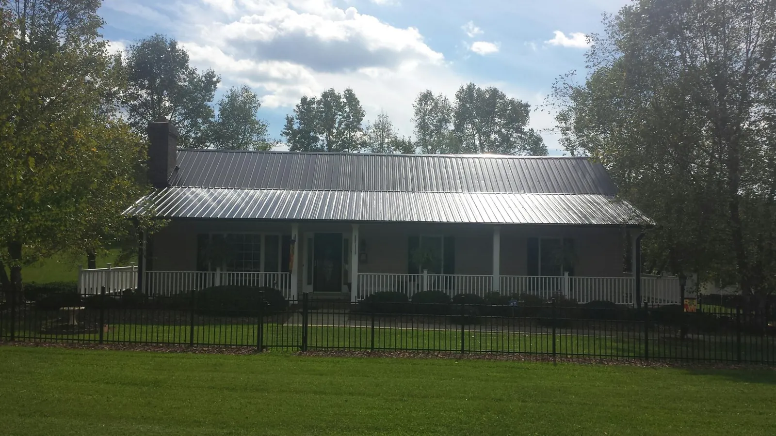 Gray metal roof on a brick ranch with a full width front porch — Gutter Guard Installation work by our crew in Lignum