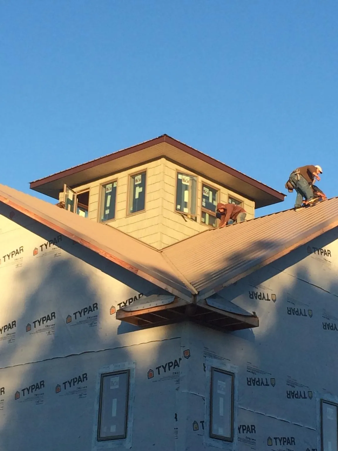 Roofers working around a rooftop cupola on a new metal roof at sunset — Roof Waterproofing in Lignum by Roofing Brothers